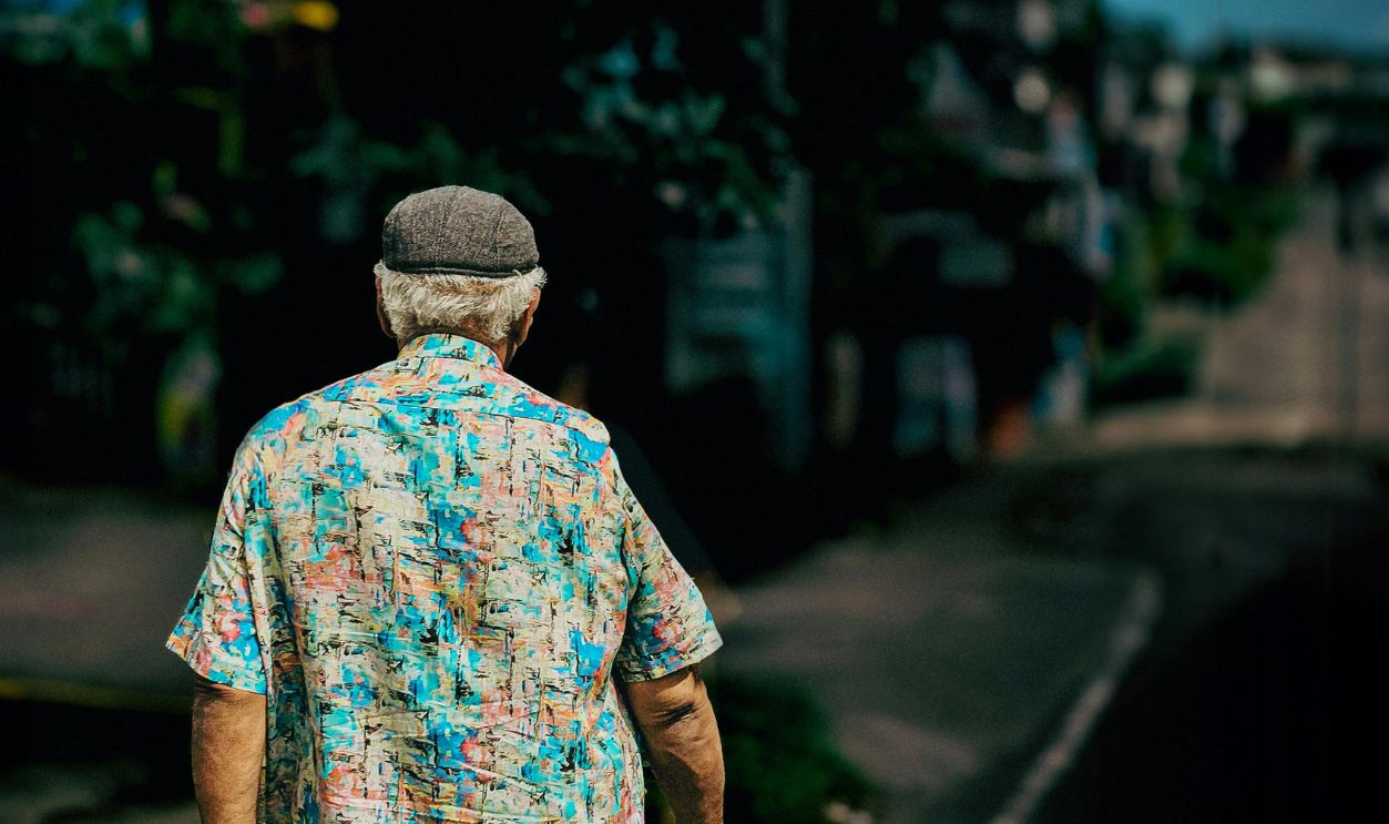 A senior man with a colorful shirt walks on a deserted street in Kochi, India, on a sunny day.