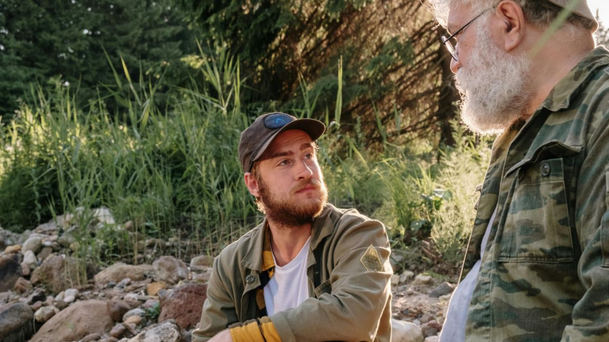 Two men enjoy leisure time together by a riverside in a natural, countryside setting