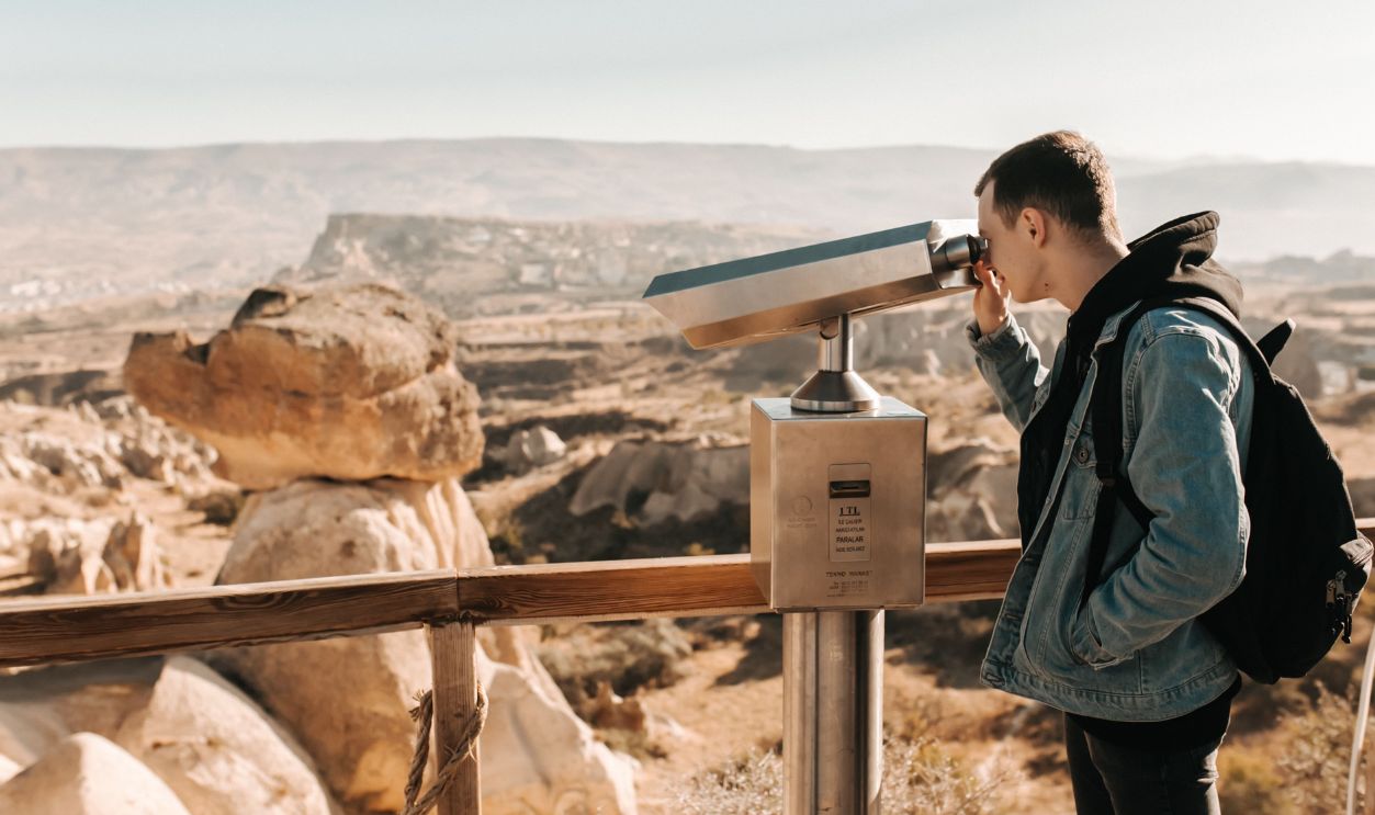 A man looks through a telescope, overlooking the unique rock formations in Cappadocia, Turkey