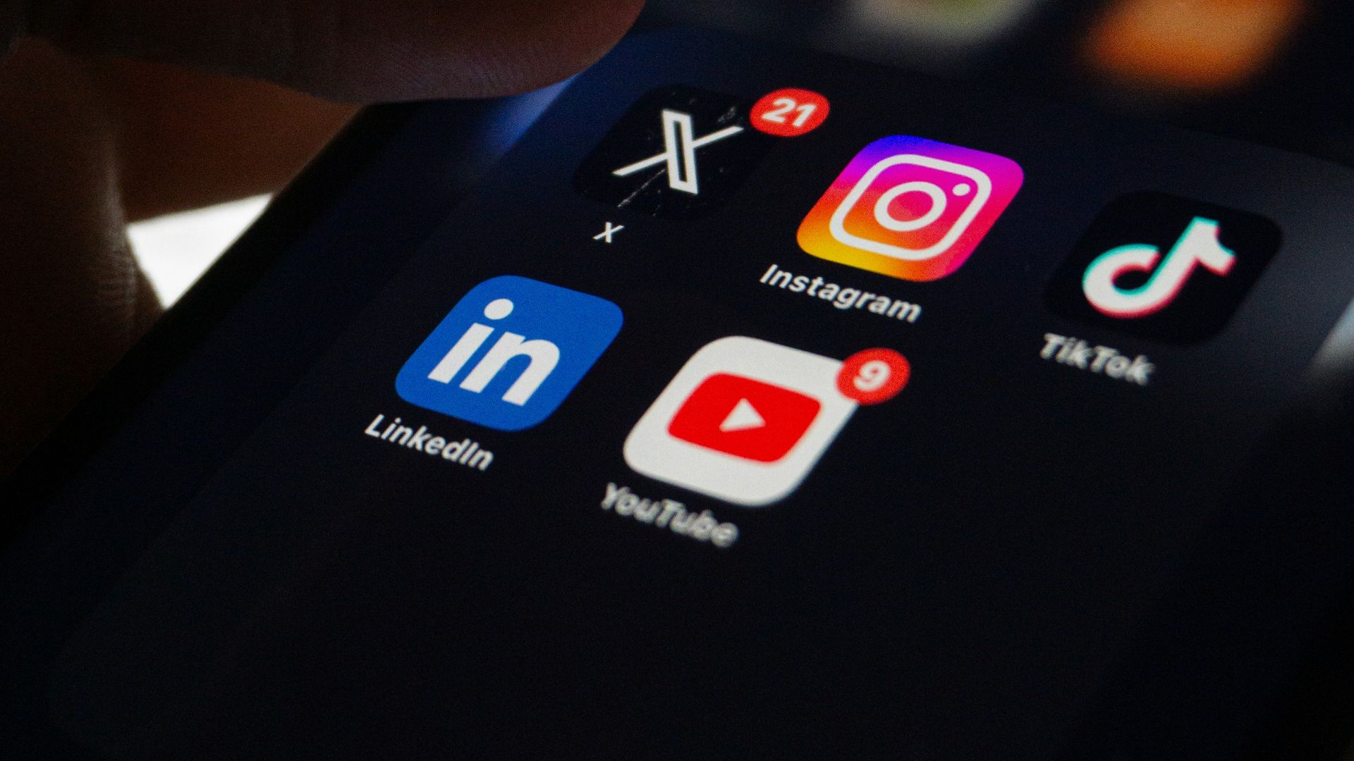 A person holding a smart phone with social media on the screen