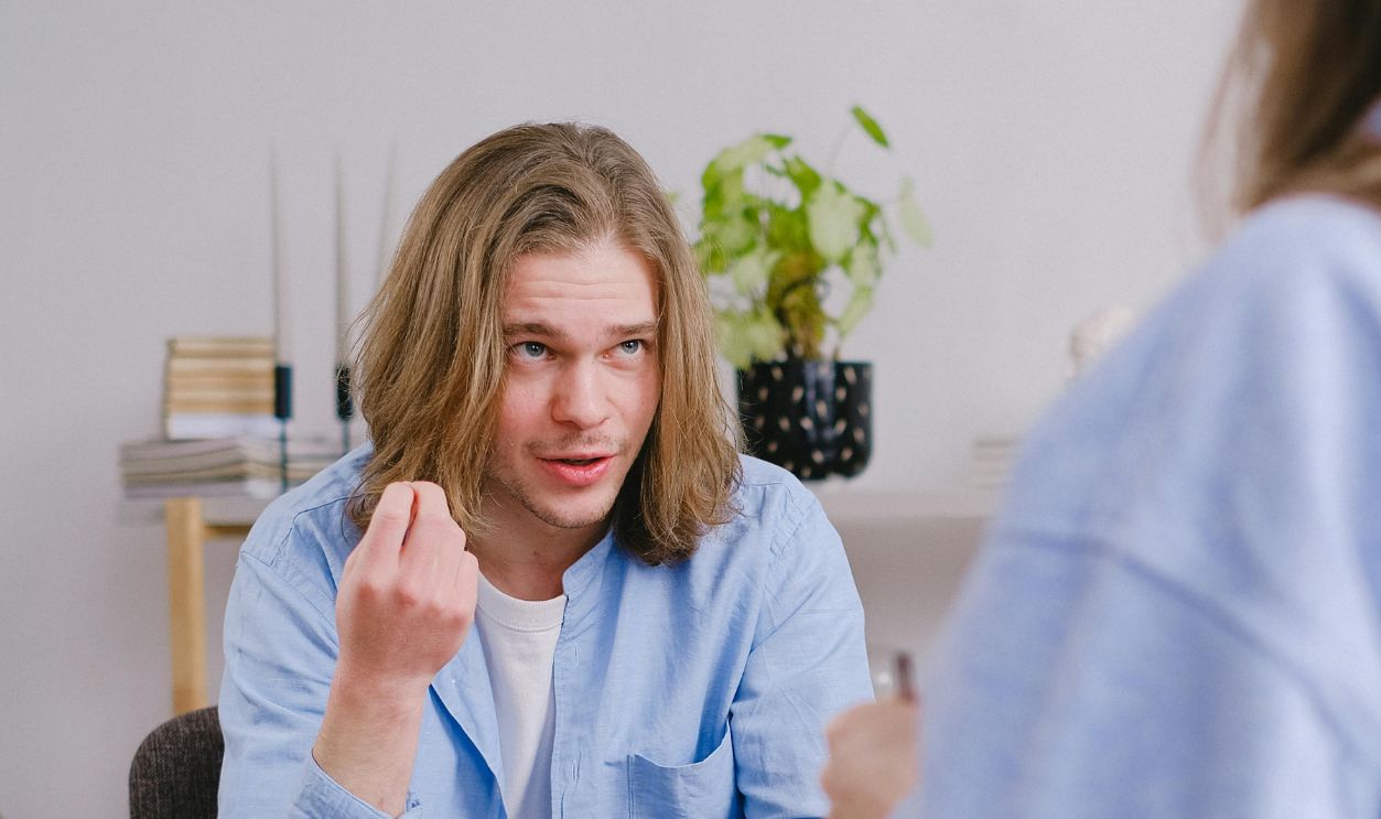 A young man in therapy, gesturing towards therapist in a comfortable setting