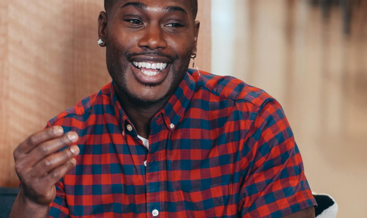 A joyful man in a plaid shirt smiles during a friendly chat, showcasing positive interactions