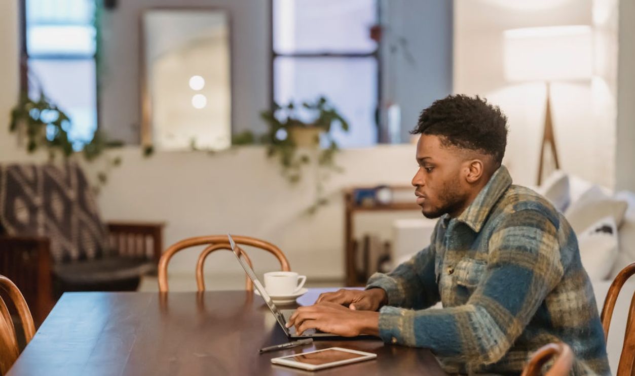 Young man deeply focused on work at laptop in a cozy living room setting