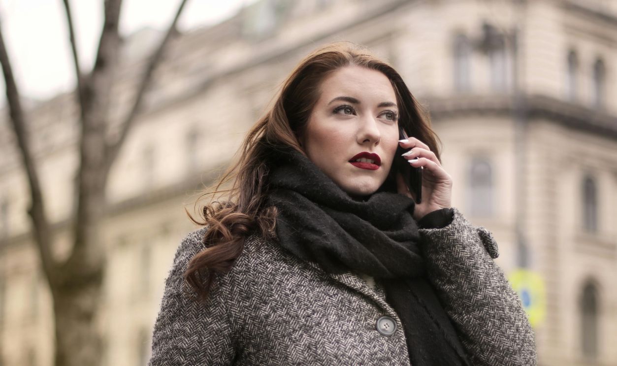 Brunette woman with shopping bags talks on her mobile outdoors in urban setting