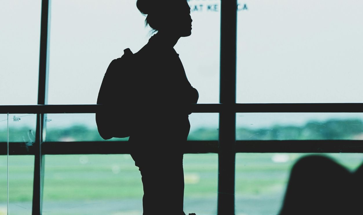Silhouette of a woman with a backpack standing at Surabaya airport terminal, Indonesia.