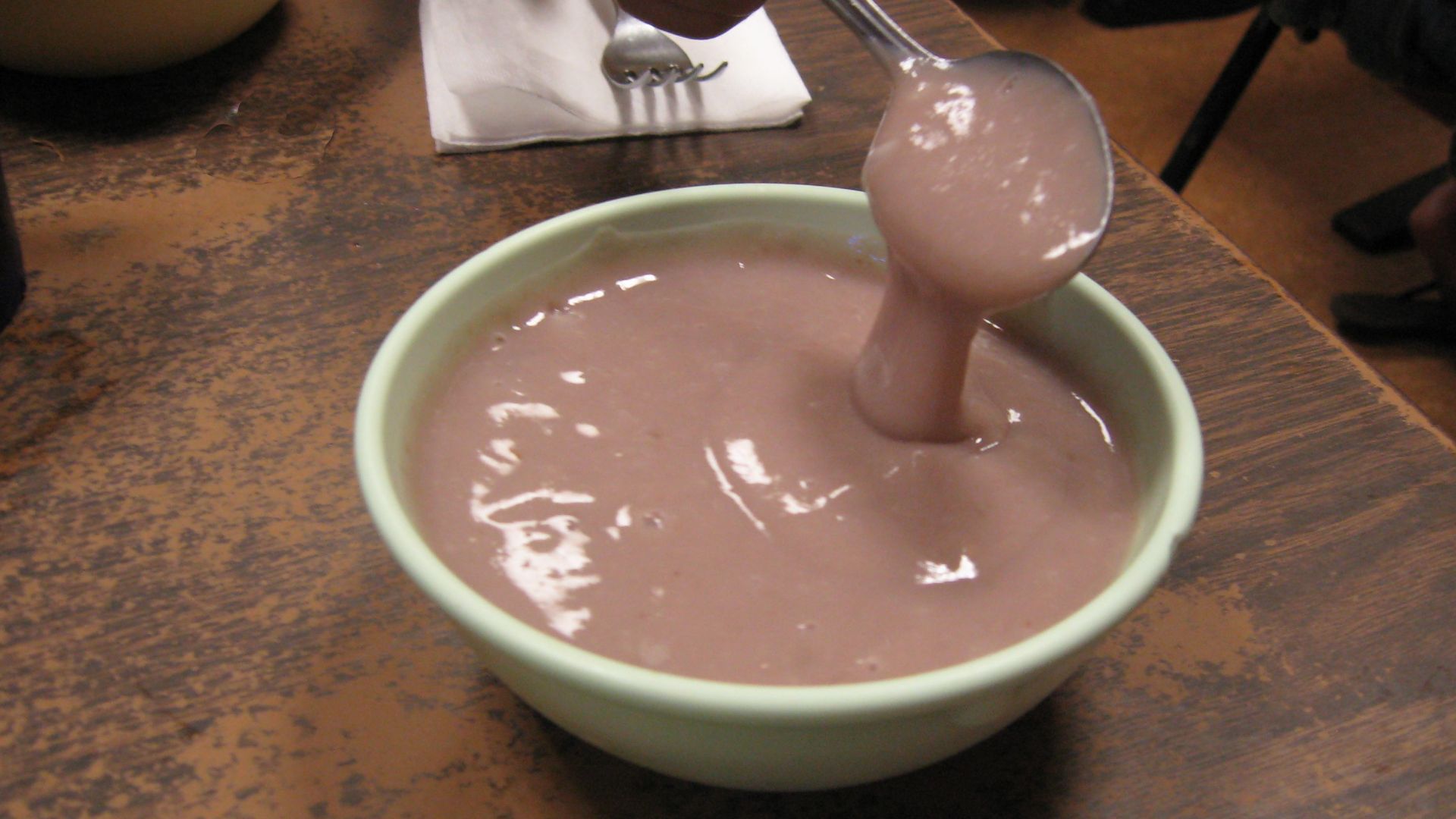 A medium-sized bowl of poi with a spoon to show consistency.