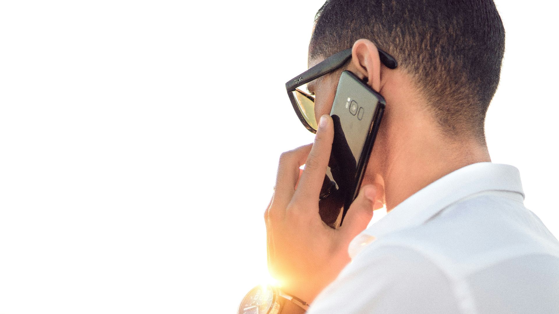man holding smartphone standing in front of calm body of water