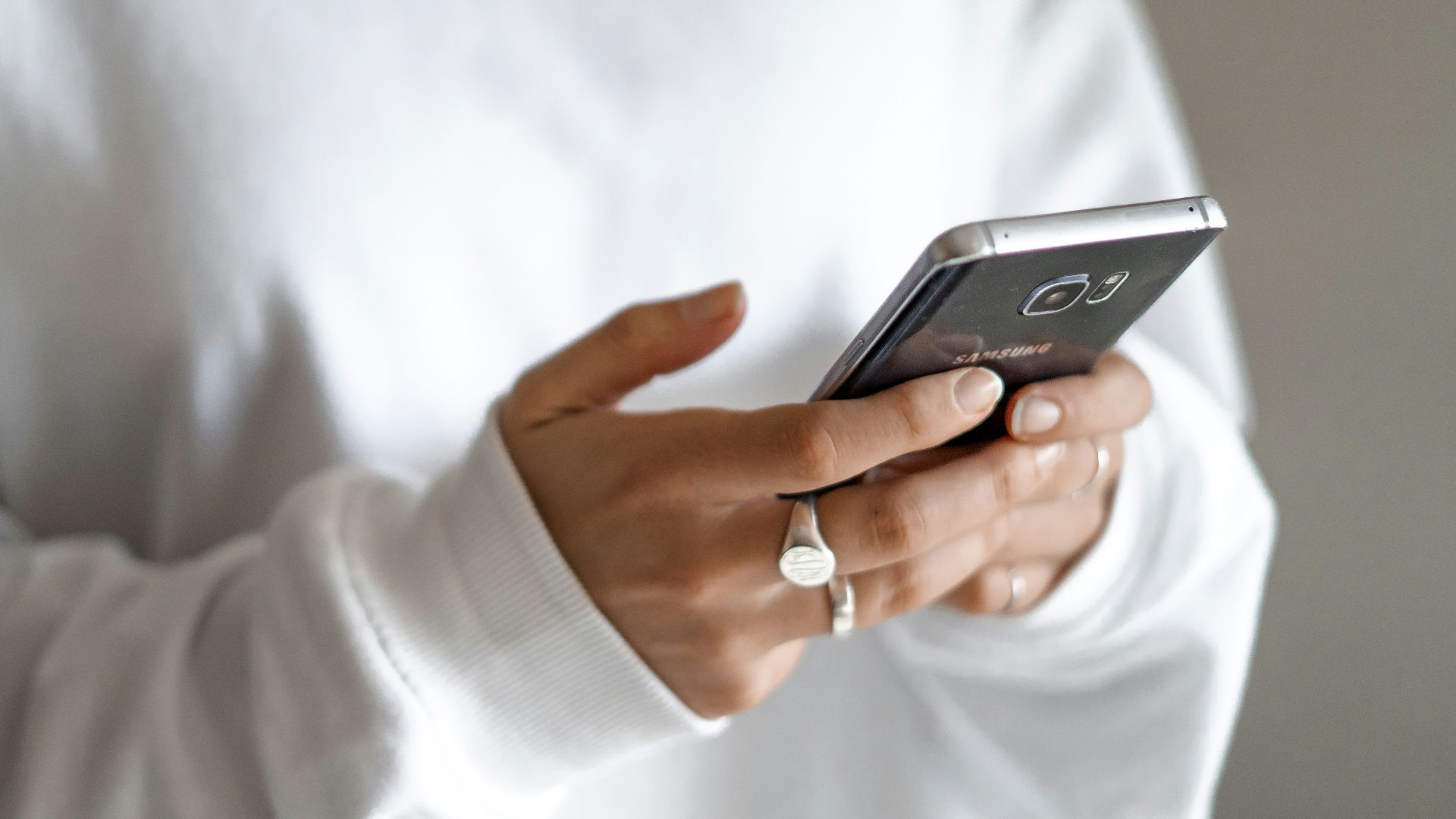 person in white long sleeve shirt holding black smartphone