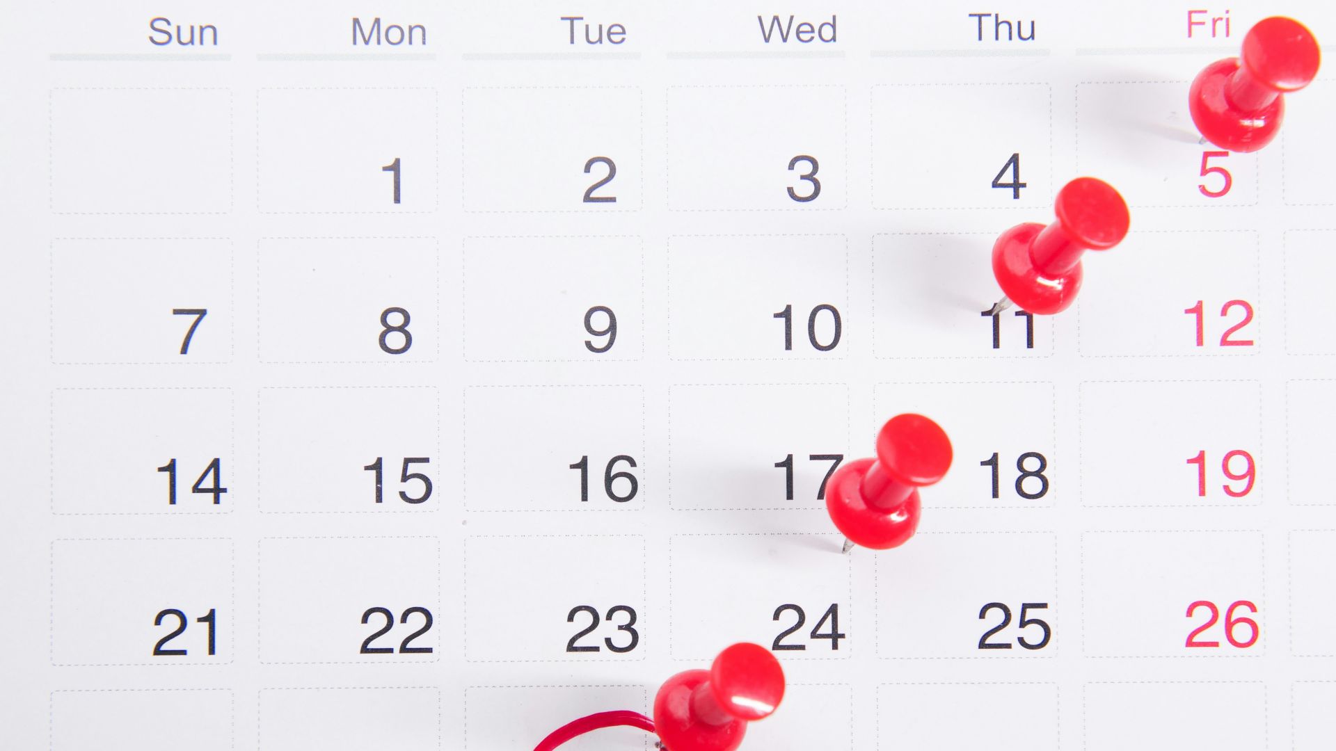 a calendar with red push buttons pinned to it