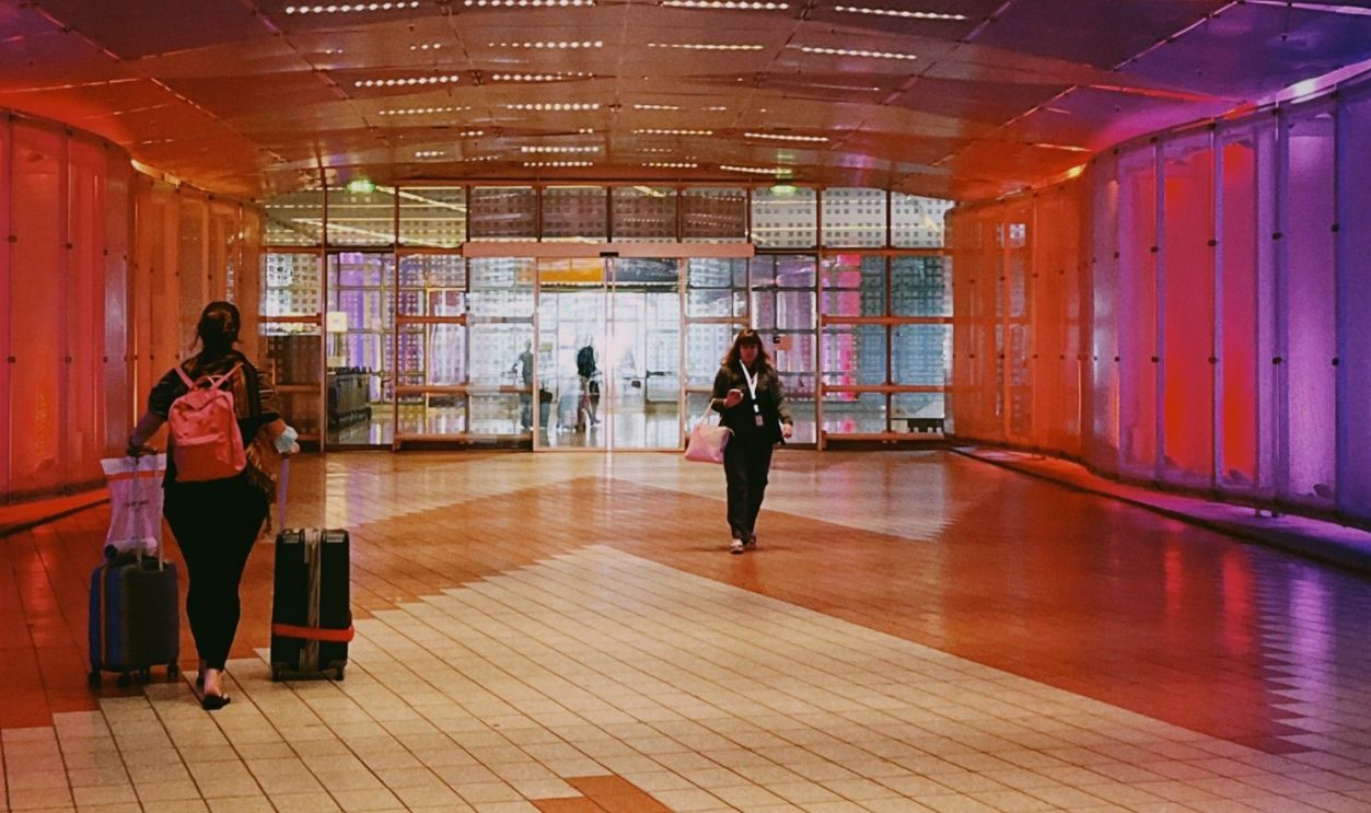Vibrant airport hallway with people and luggage, offering a lively atmosphere.