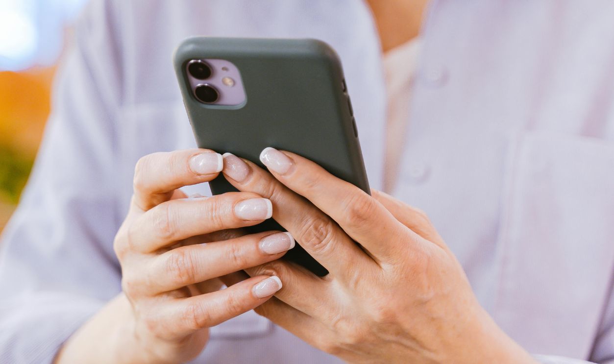 Close-up of a mature woman with short hair using a smartphone indoors, selective focus