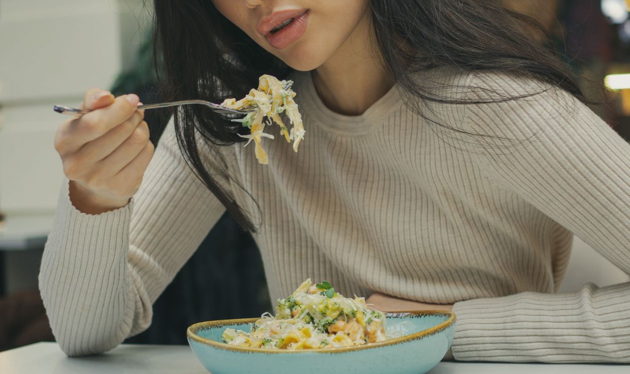 Young woman dining indoors with pasta in a casual restaurant setting