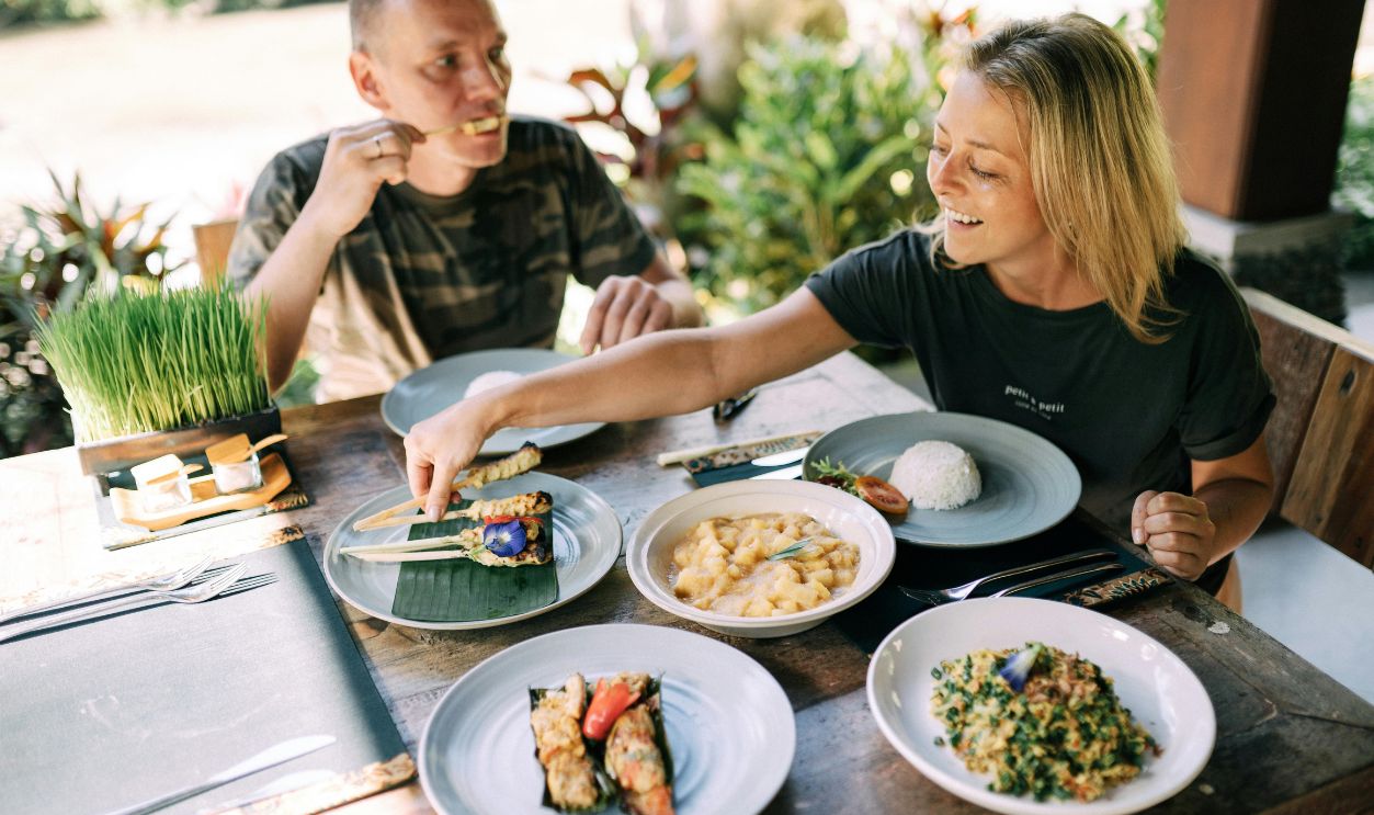 A couple enjoying a variety of Asian dishes outdoors at a cozy table setting