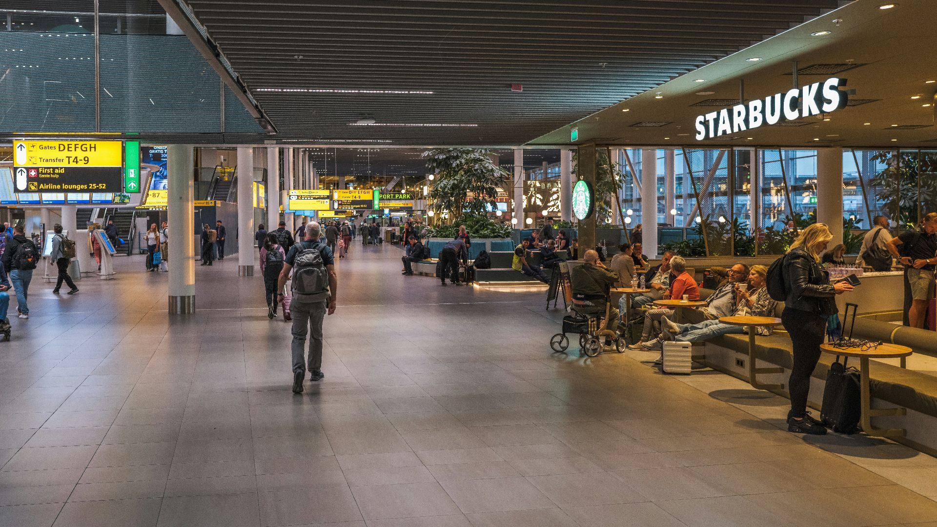 People at a starbucks in a modern airport terminal.