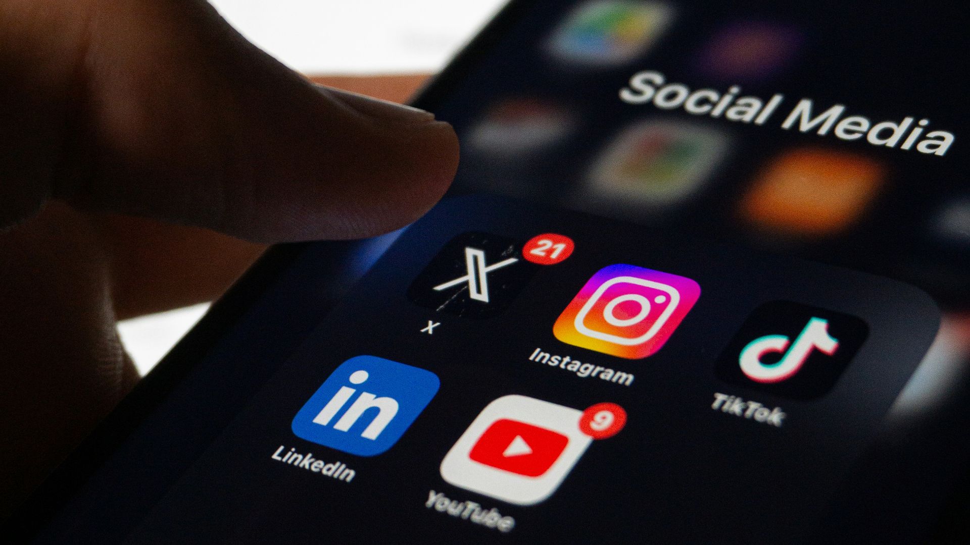 A person holding a smart phone with social media on the screen