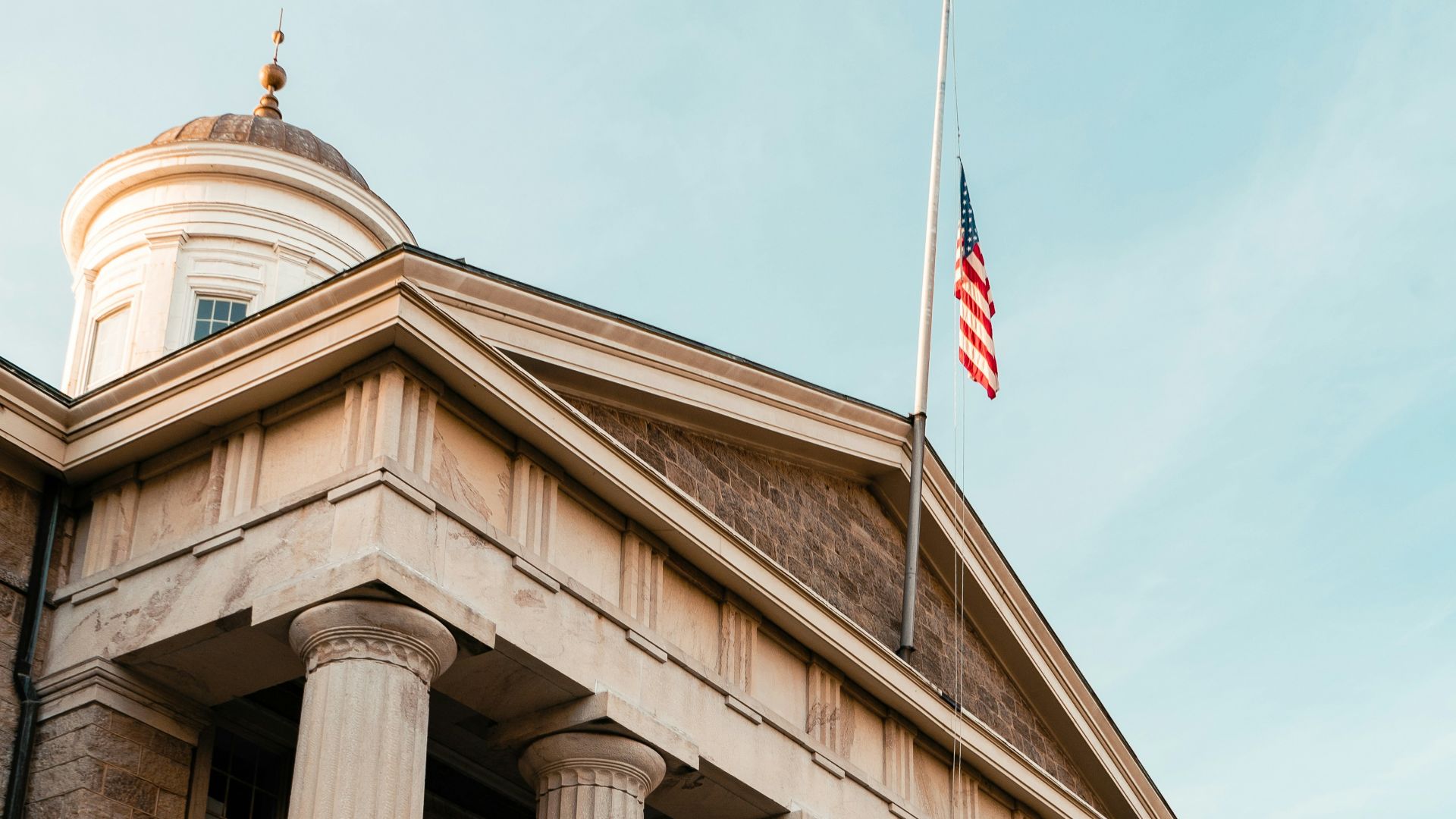 a building with columns and a flag on top