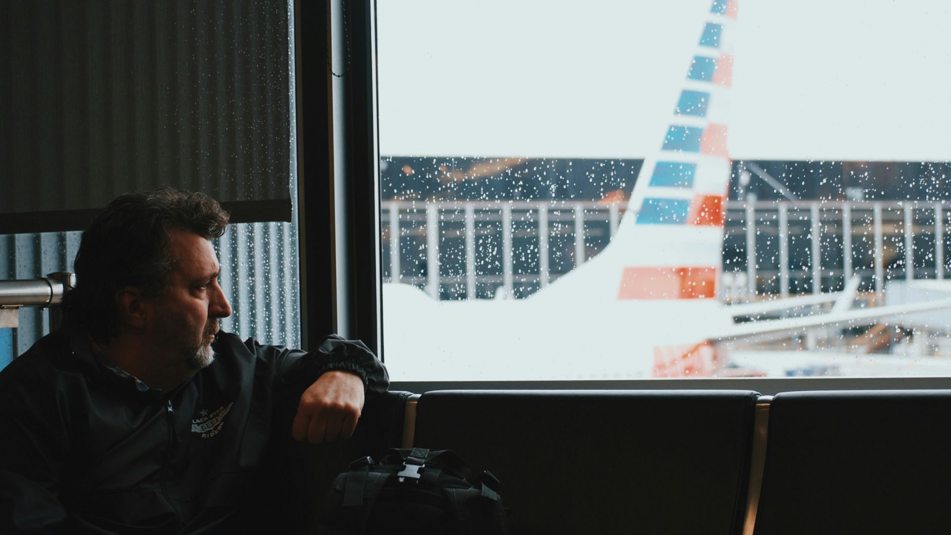 man sitting in airport watching airplane during daytime