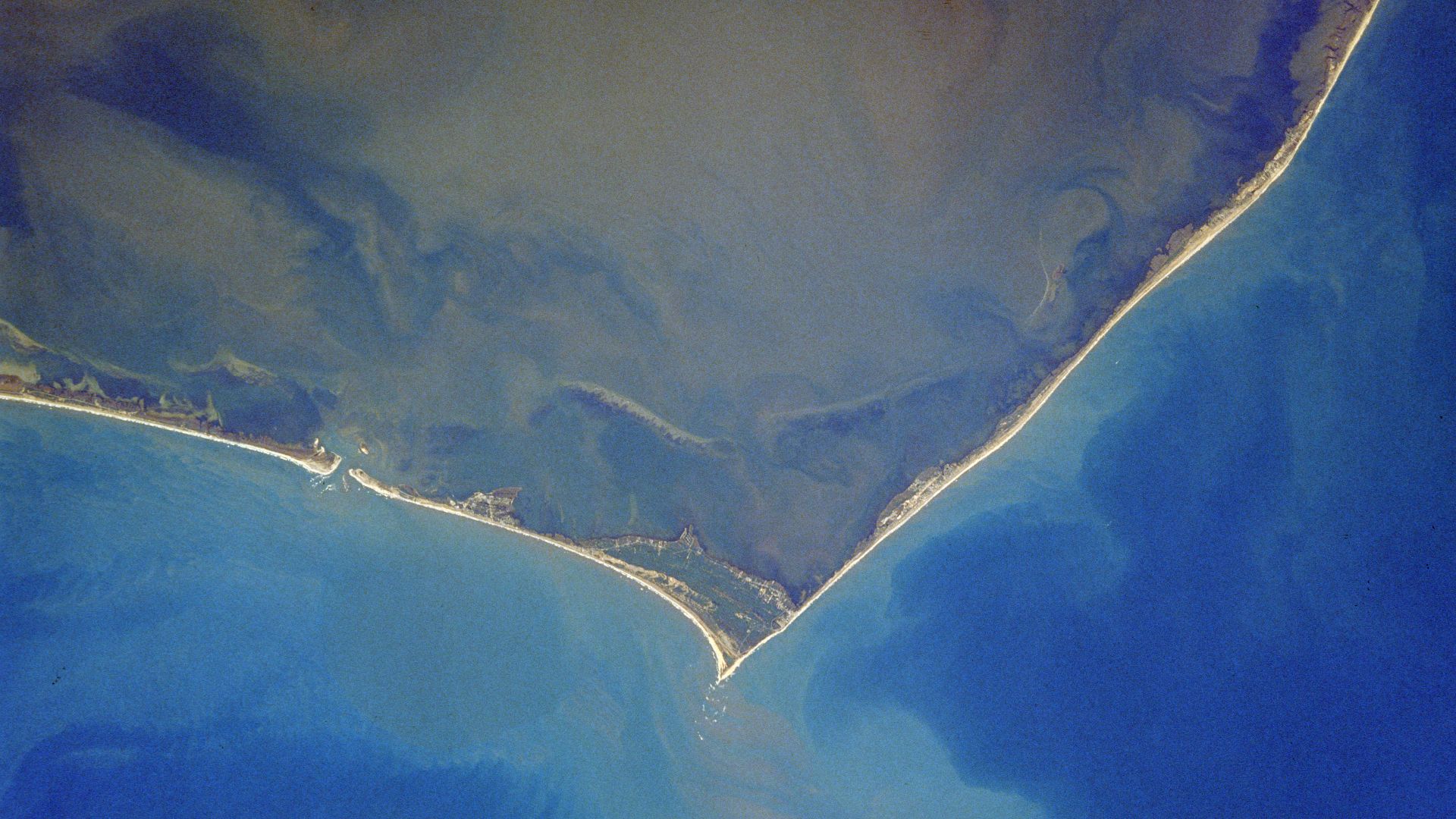 Cape Hatteras, North Carolina, USA - October 1989
The famous barrier island coast of Cape Hatteras, is visible in this near vertical of the North Carolina coast. This barrier island system is protected as the Cape Hatteras National Seashore, with Pamlico
