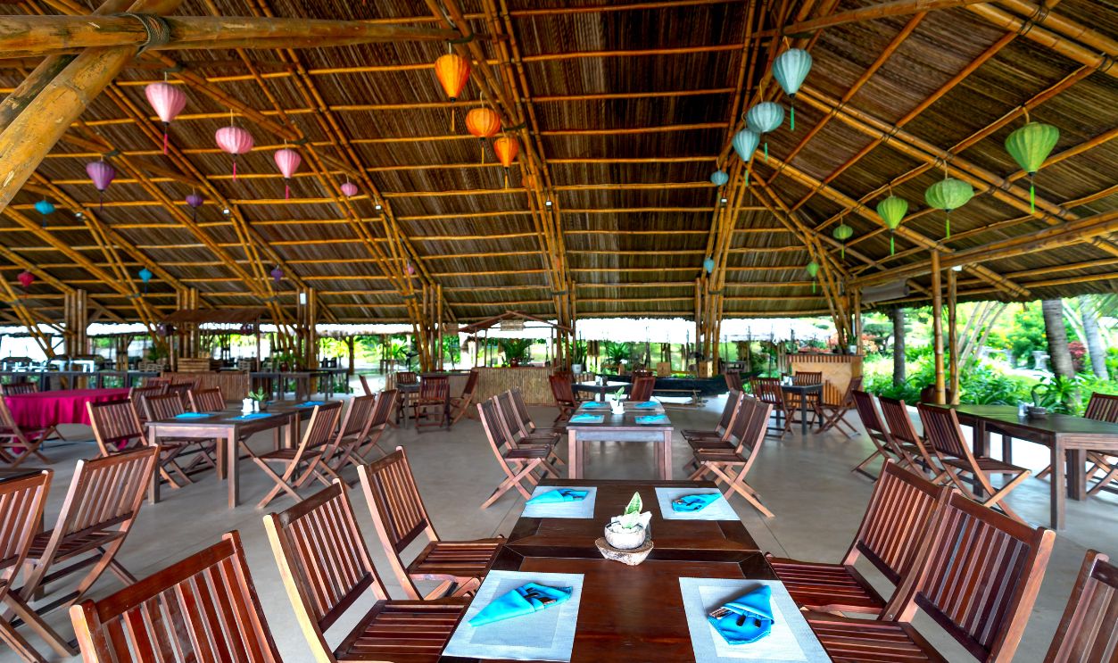 Spacious bamboo pavilion decorated with vibrant lanterns and wooden furniture for a tropical ambiance