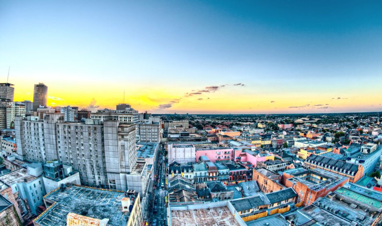 A colorful aerial view of New Orleans cityscape during sunset, showcasing historic buildings and skyline