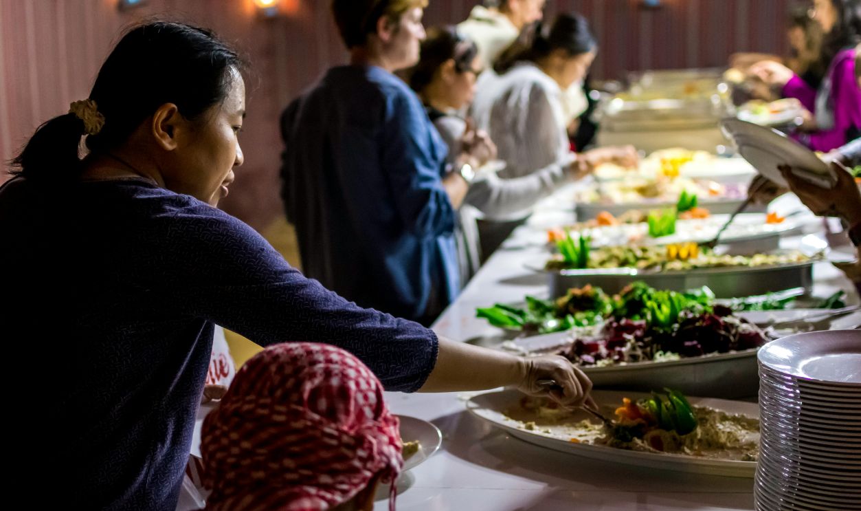 A diverse group of people enjoying a buffet dinner indoors with various dishes