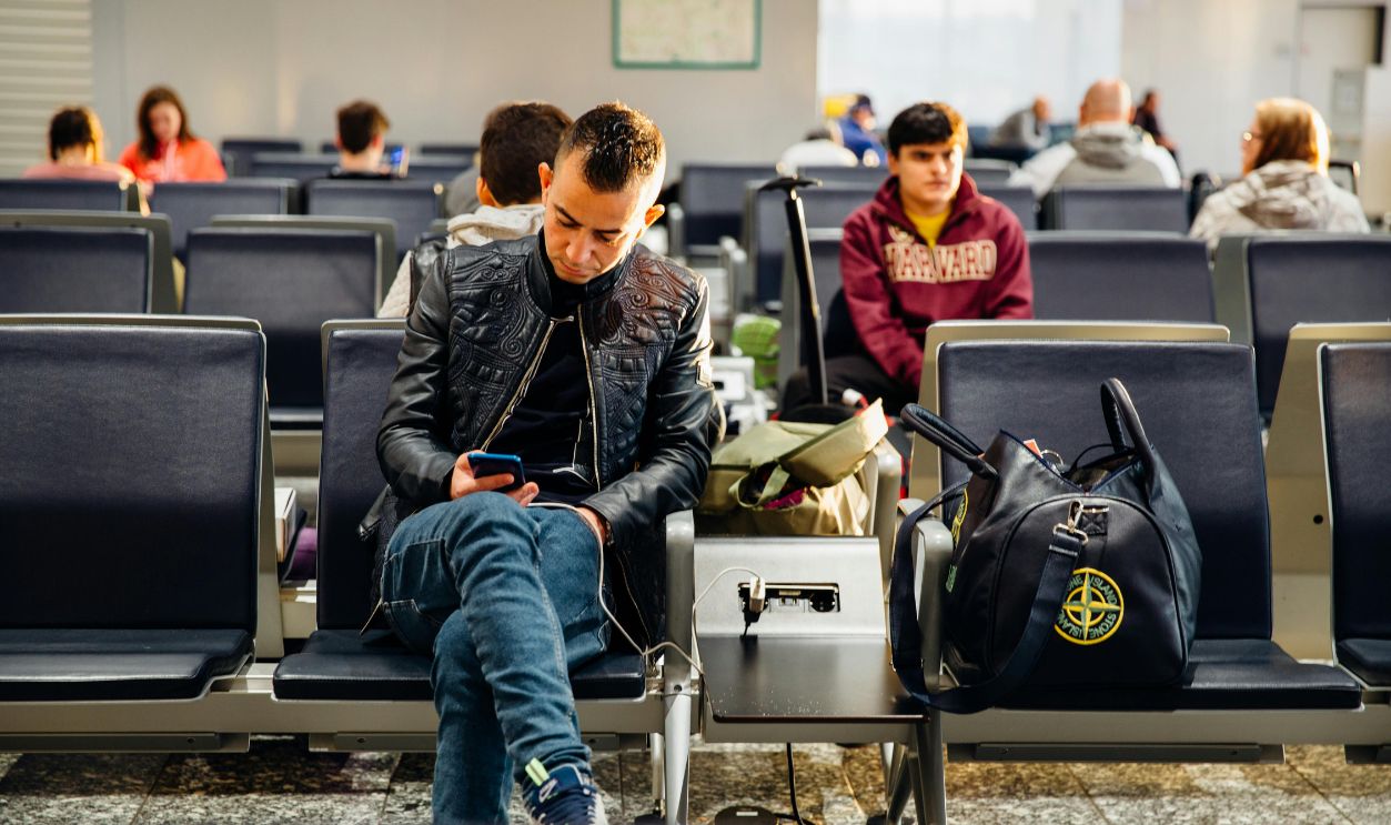 People sitting in an airport lounge, focused on smartphones