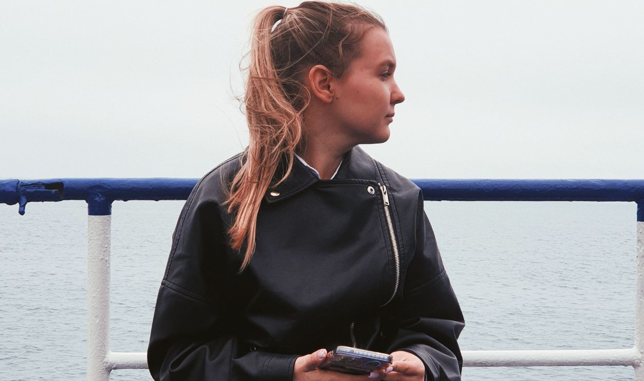 A woman sitting on a cruise ship deck looking at the sea