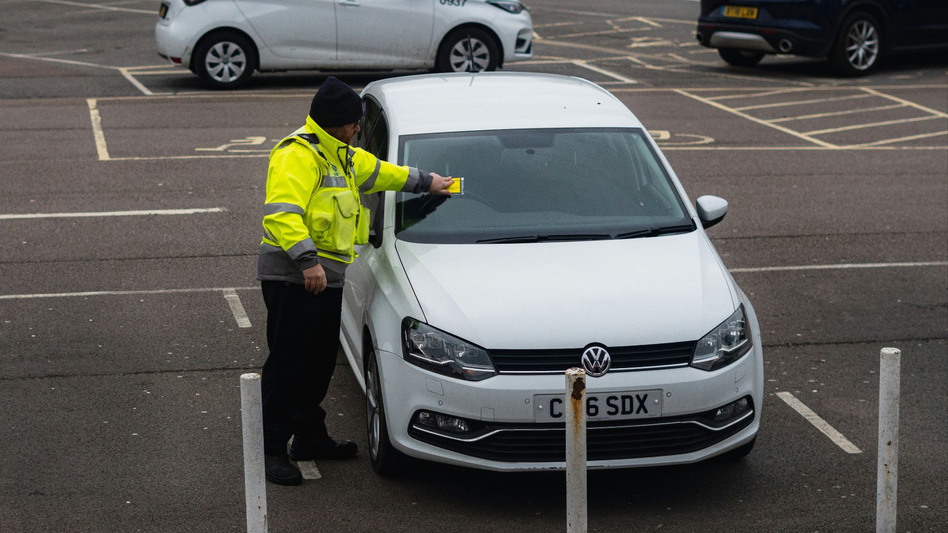 man in yellow jacket standing beside white car
