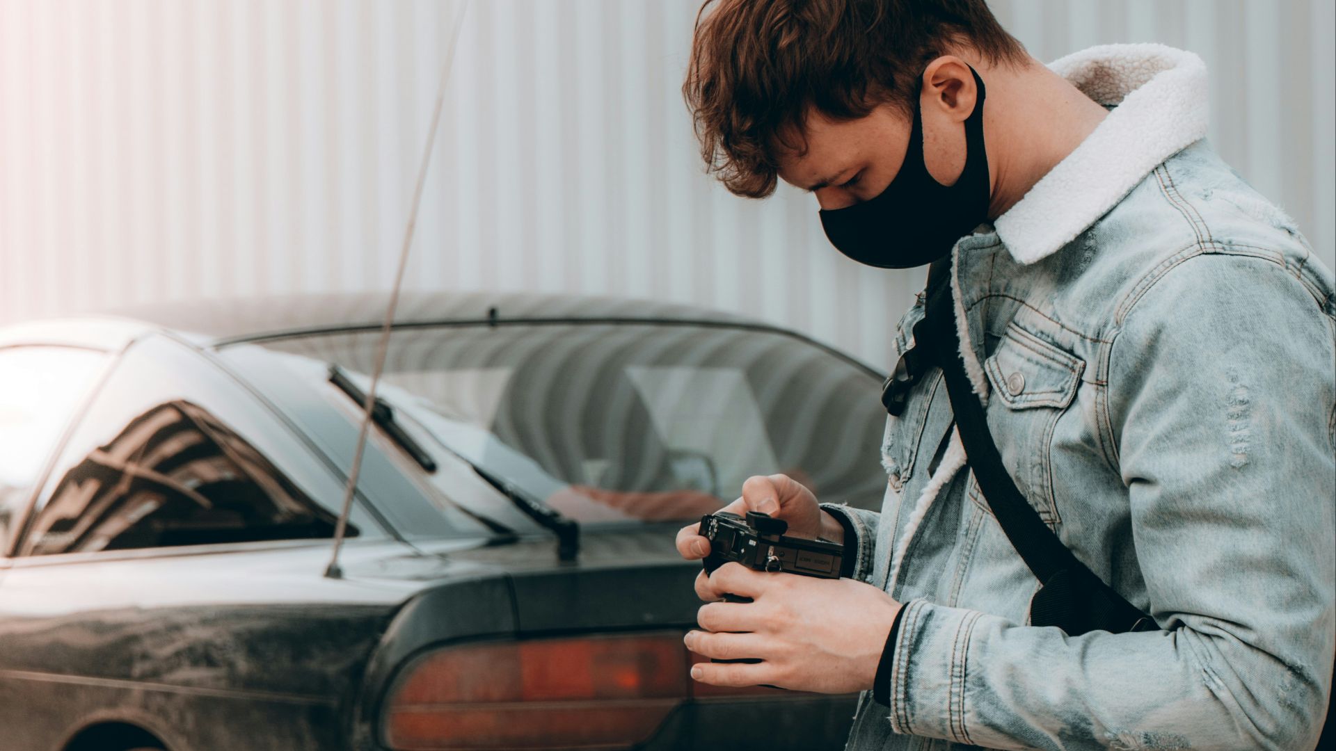 man in gray coat holding black car
