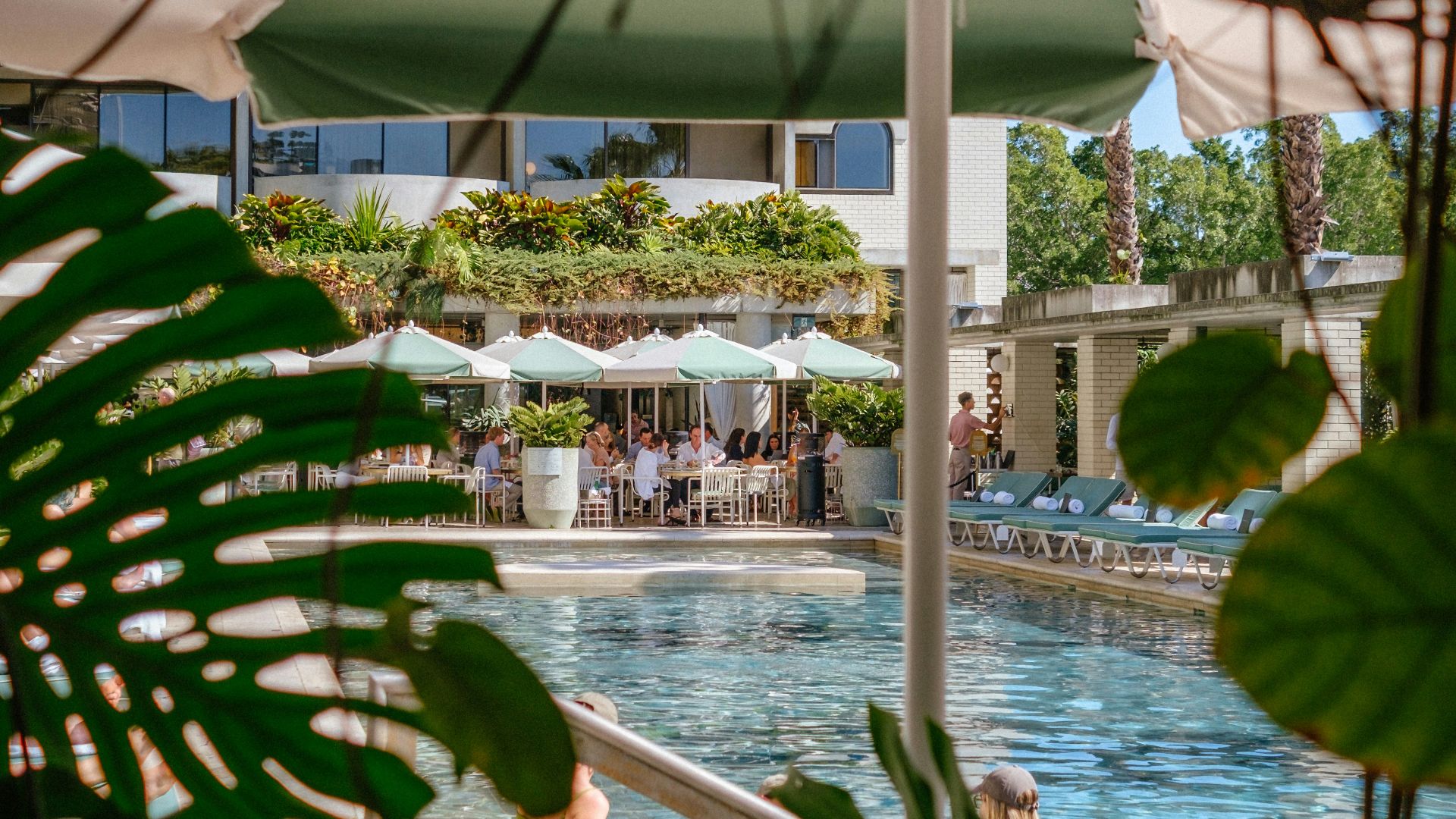People relaxing by a tropical resort swimming pool.