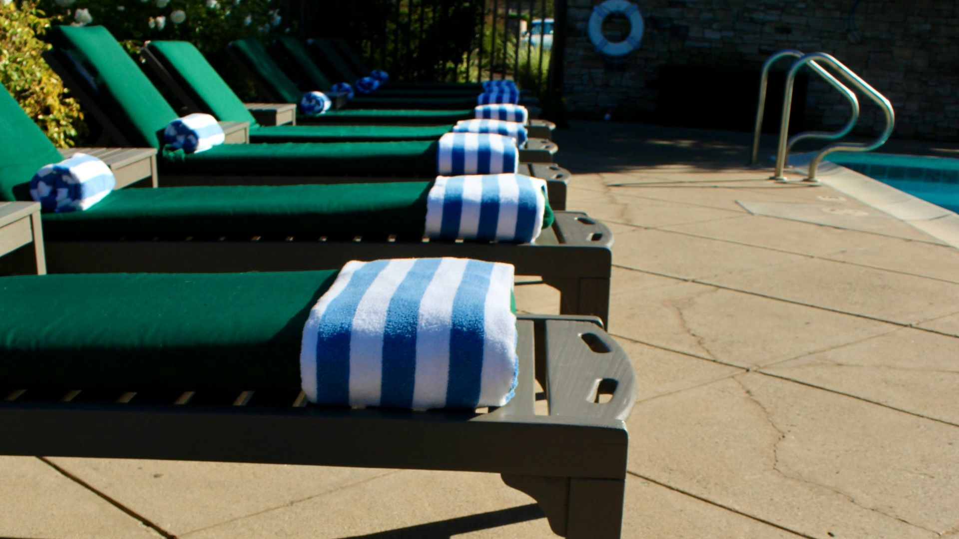 Lounge chairs with towels by a swimming pool.