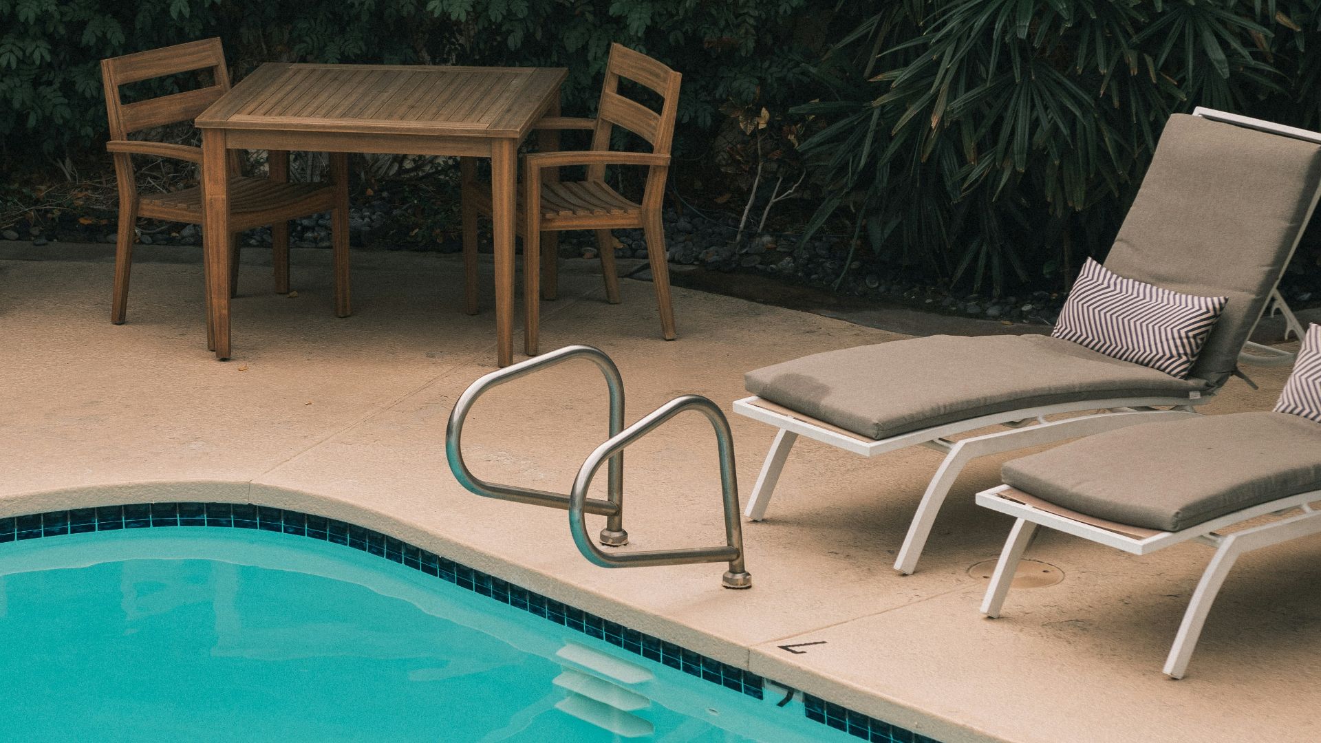 two gray sunbathing loungers beside pool