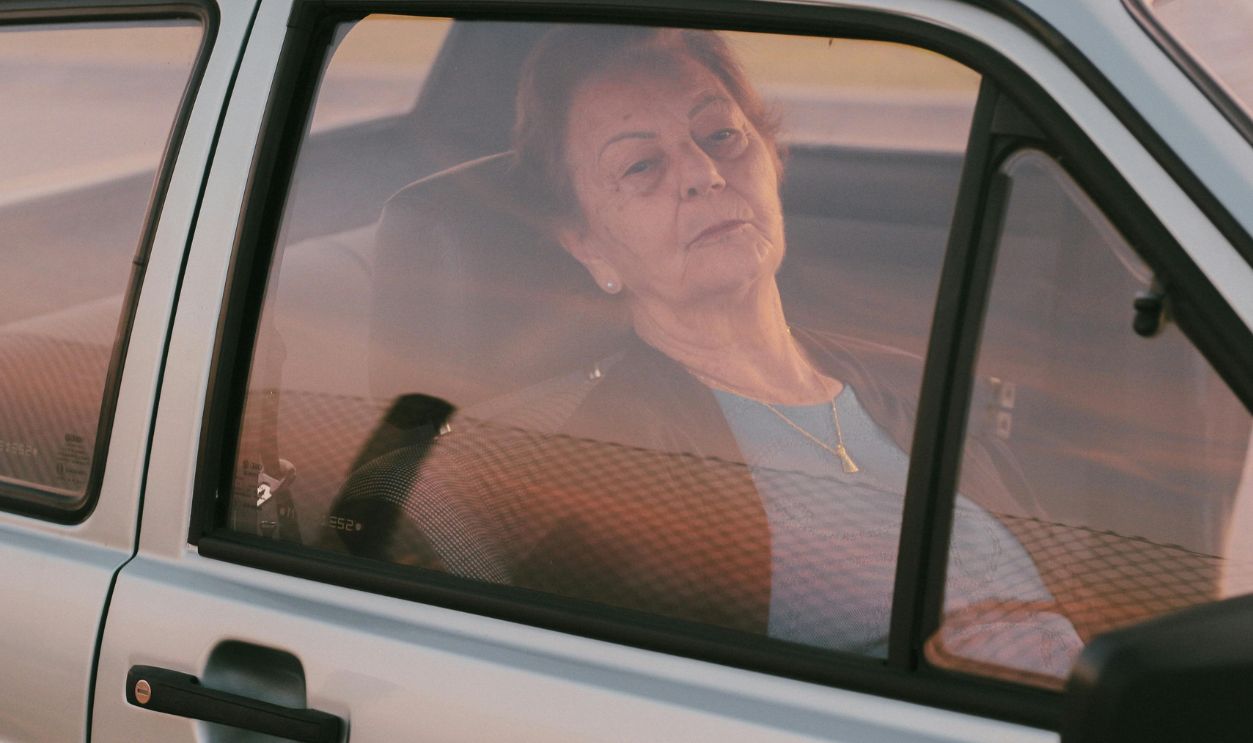 Senior woman gazing out a car window, captured in a serene and contemplative moment