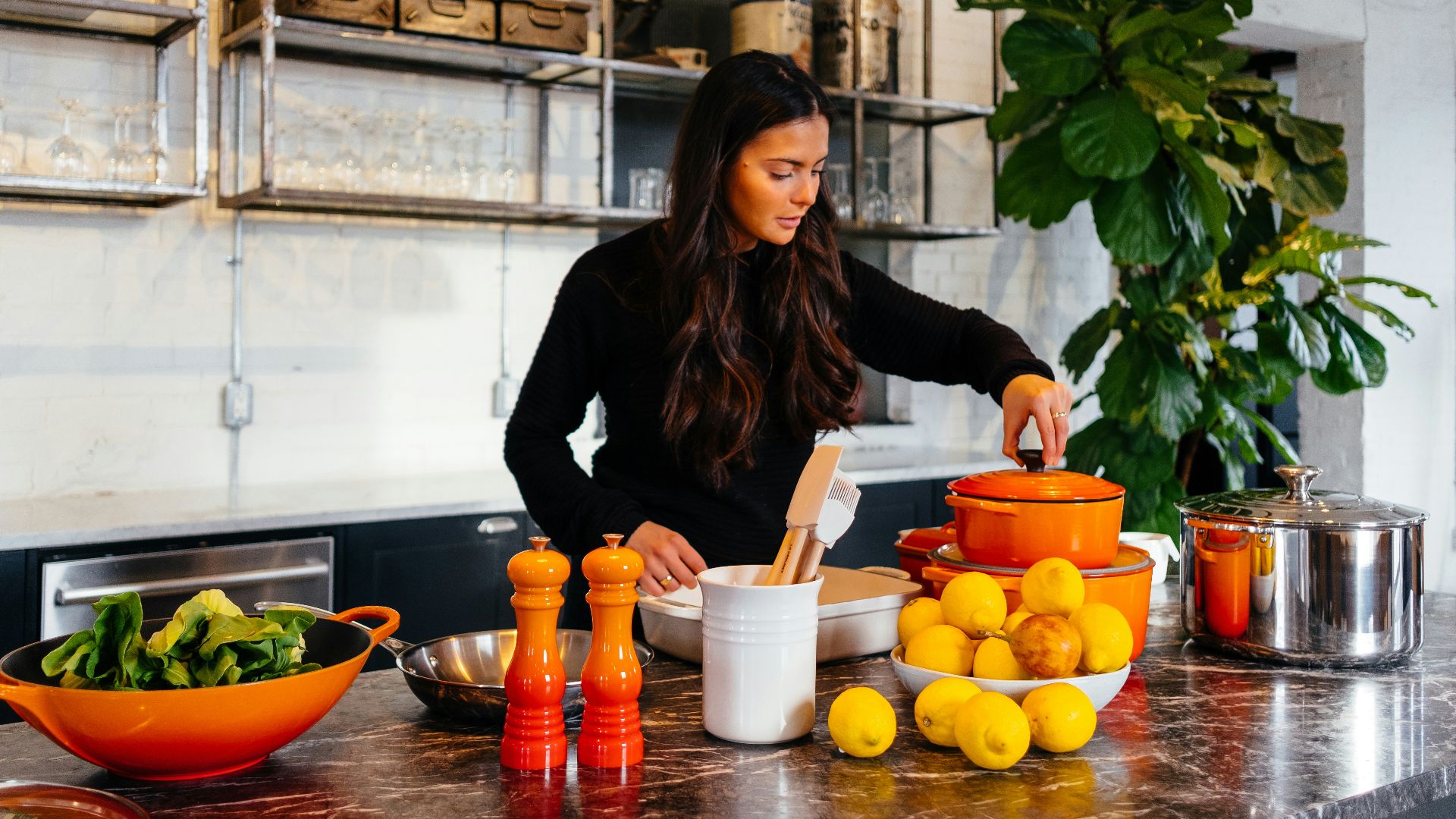 woman standing in front of fruits holding pot's lid