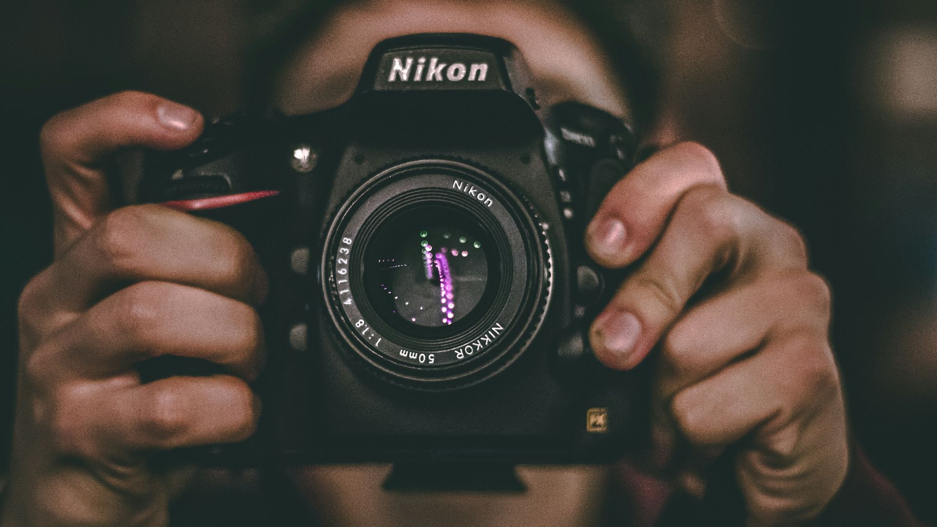 person's face being covered by Nikon DSLR camera