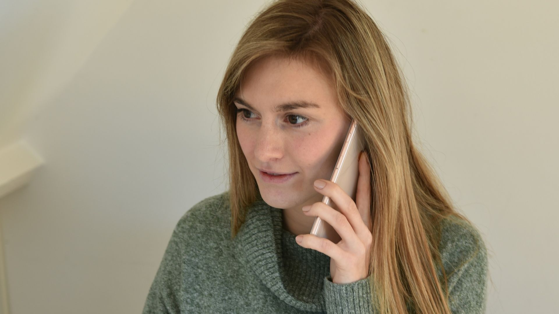 a woman sitting in front of a computer talking on a cell phone