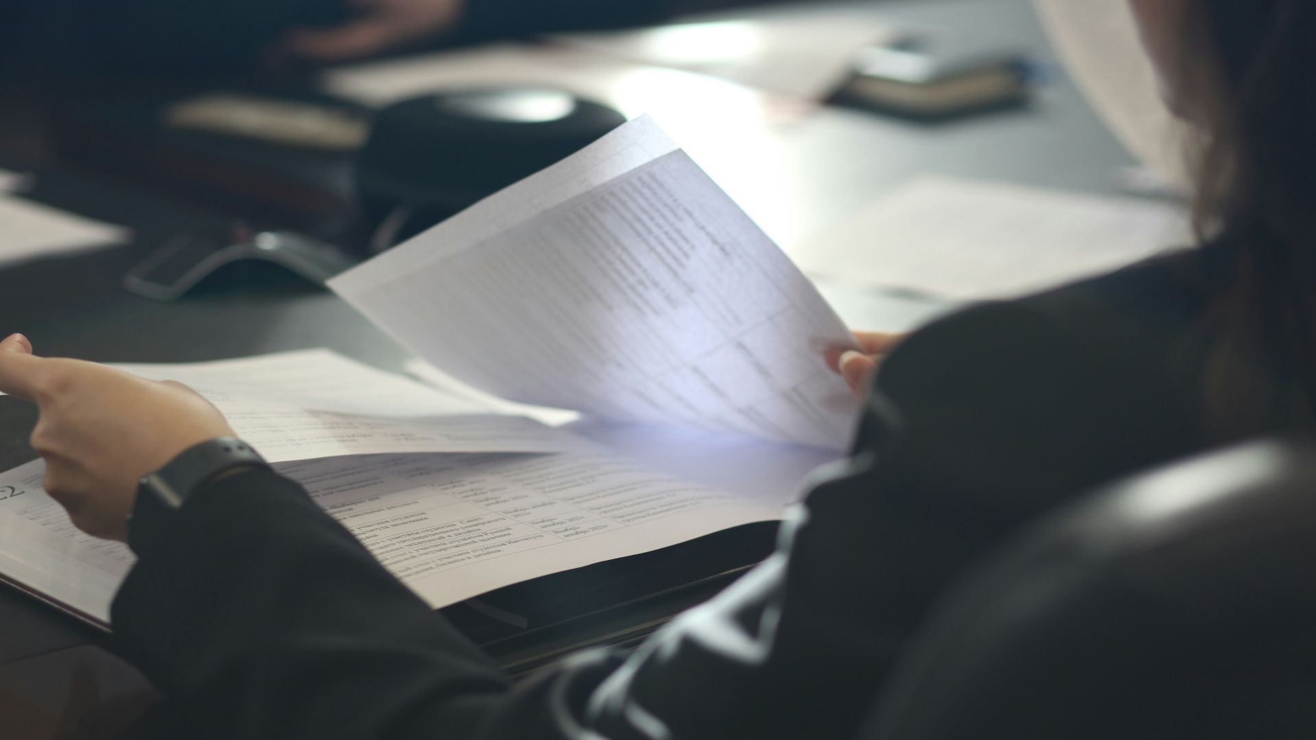 a woman sitting at a table reading a paper