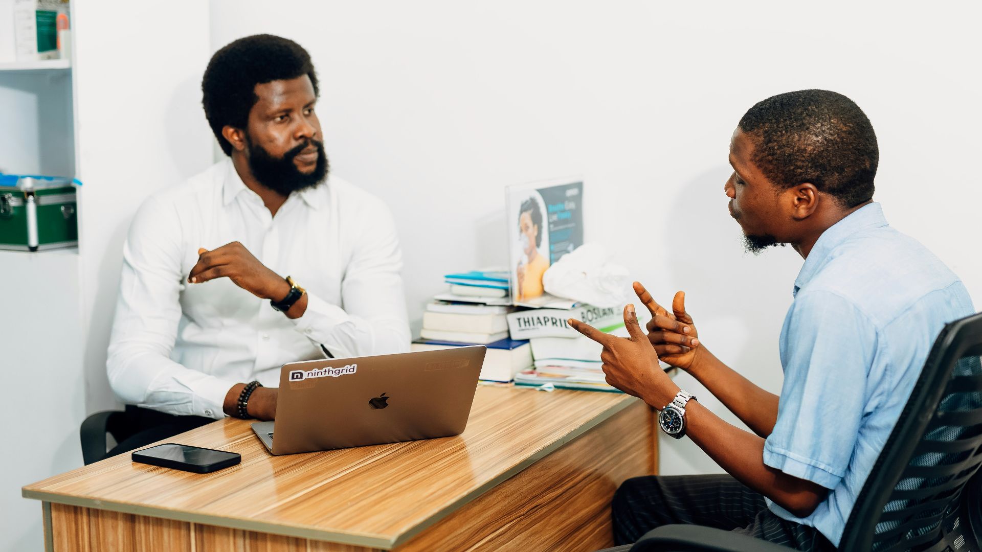 Two men sitting at a desk talking to each other