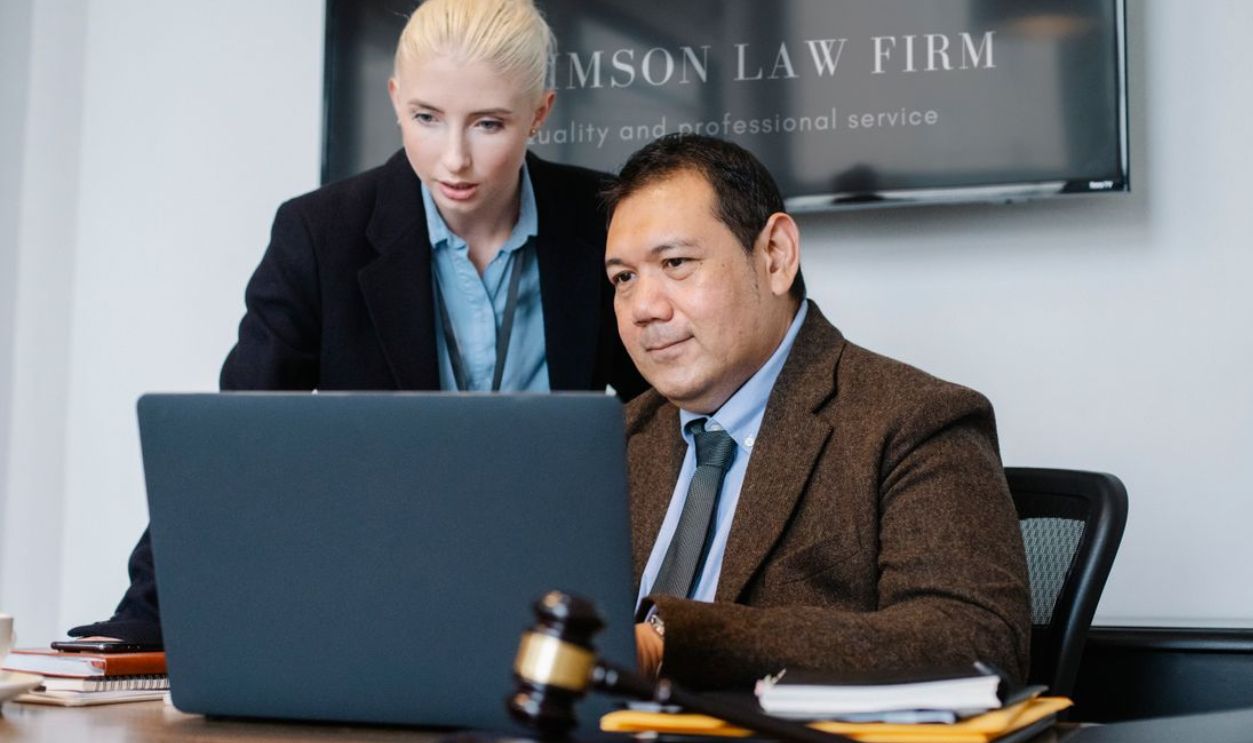 Two lawyers discussing a case at a law firm office with a laptop, dressed formally