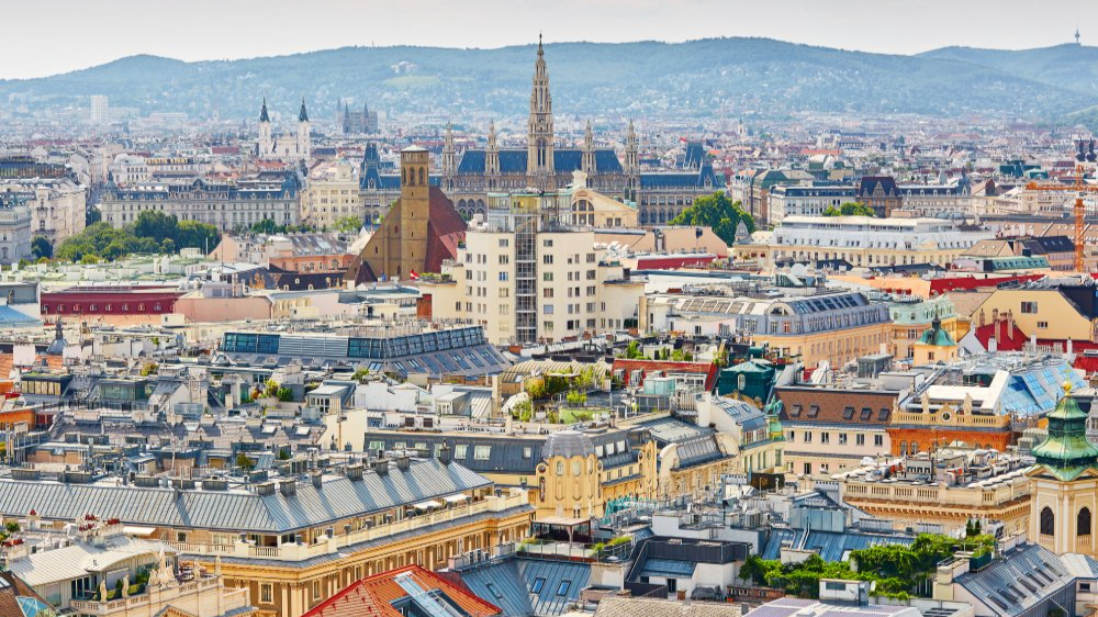 The image showcases a Vibrant urban scene of Vienna, Austria captured from a high vantage point. The city appears well-developed with a mix of modern and historic architecture.