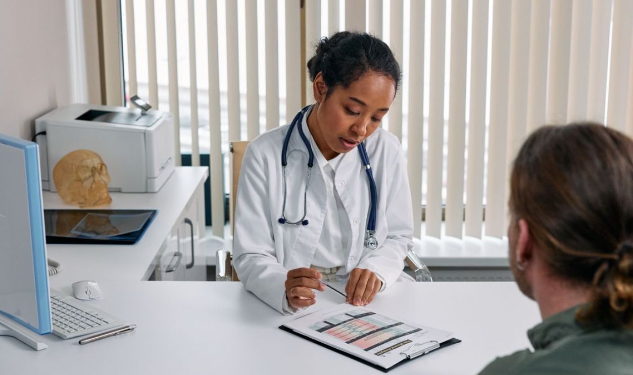 A doctor consulting with a patient in an office, discussing a medical chart.