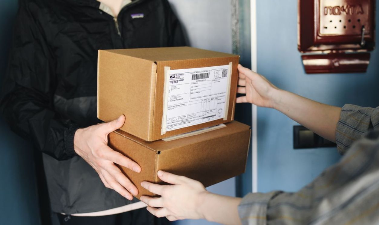 Close-up of hands exchanging cardboard boxes indoors, symbolizing delivery service.