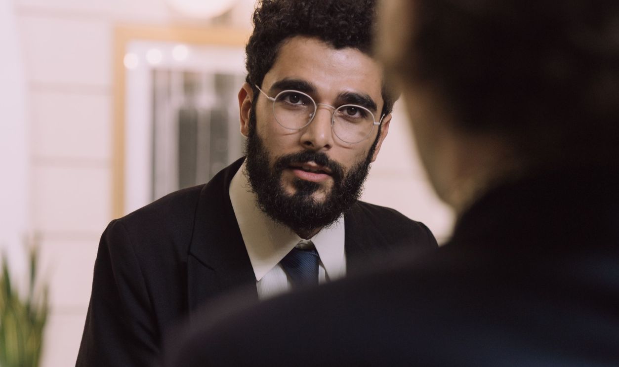 A professional businessman checks in at a hotel reception, engaging with a concierge