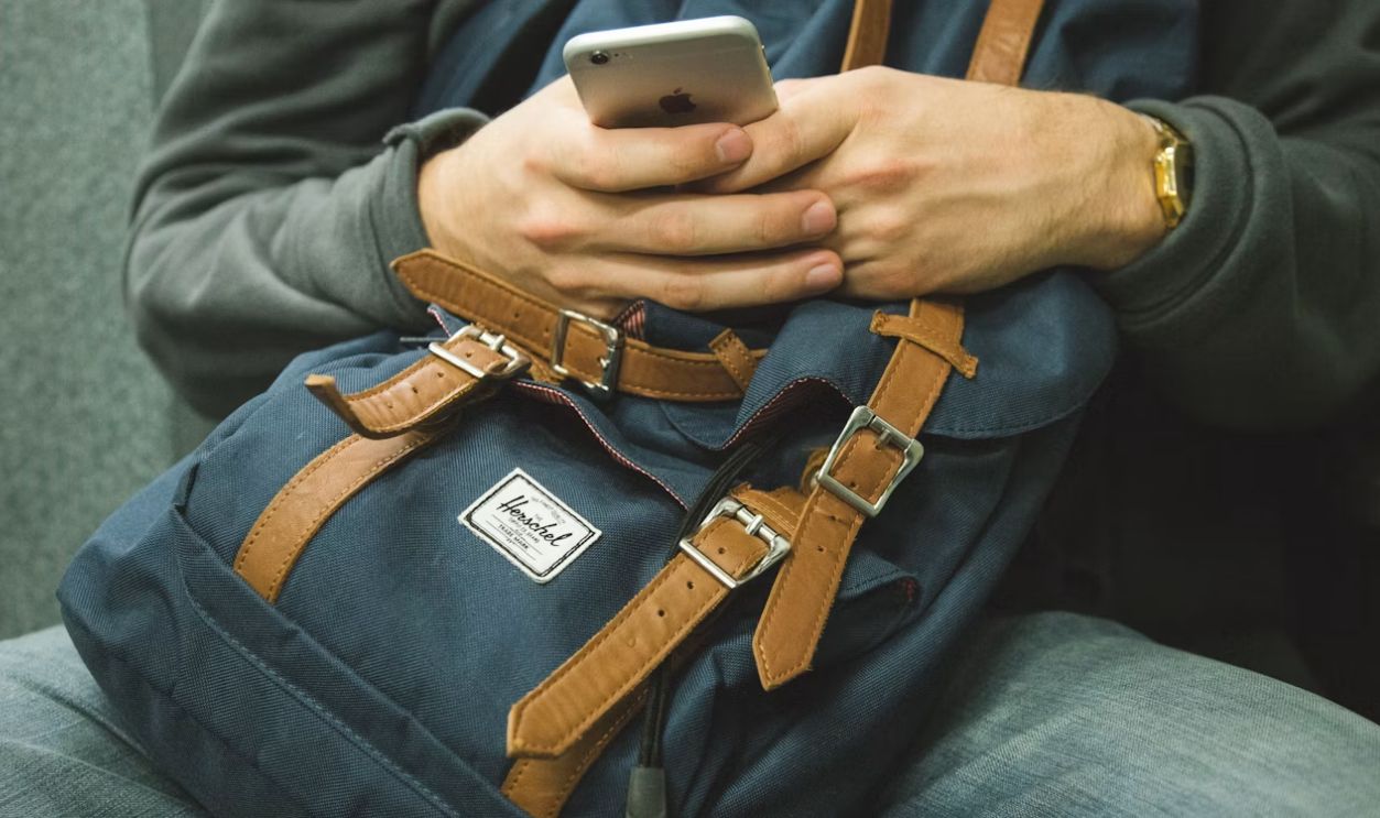 man holding his phone while sitting on chair