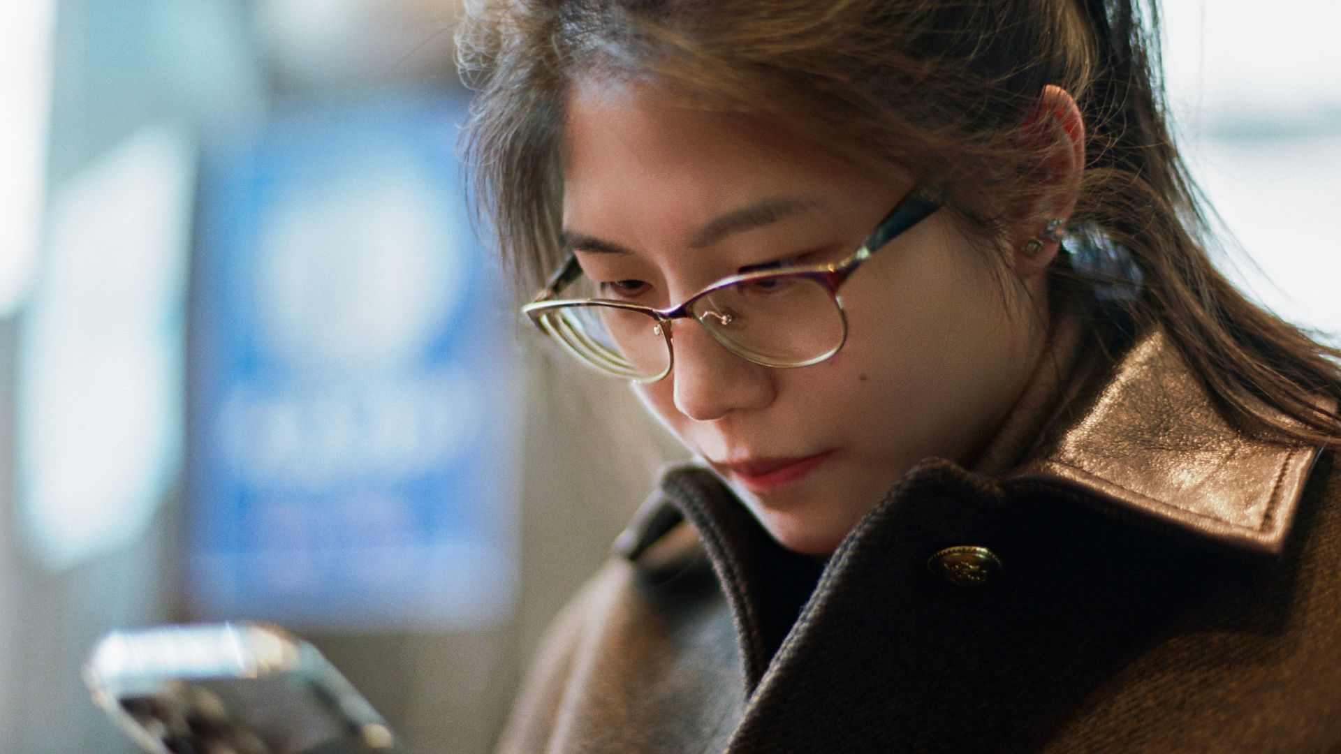 A woman wearing glasses looking at her cell phone