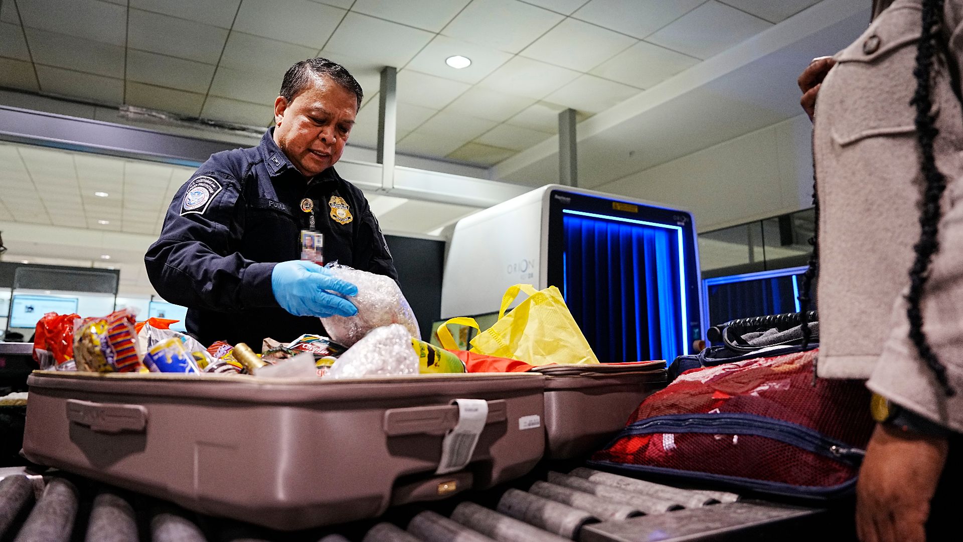 A U.S. Customs and Border Protection Office of Field Operations agriculture specialist searches the luggage of international travelers arriving at Baltimore/Washington International Thurgood Marshall Airport February 27, 2025. CBP Photo by Glenn Fawcett