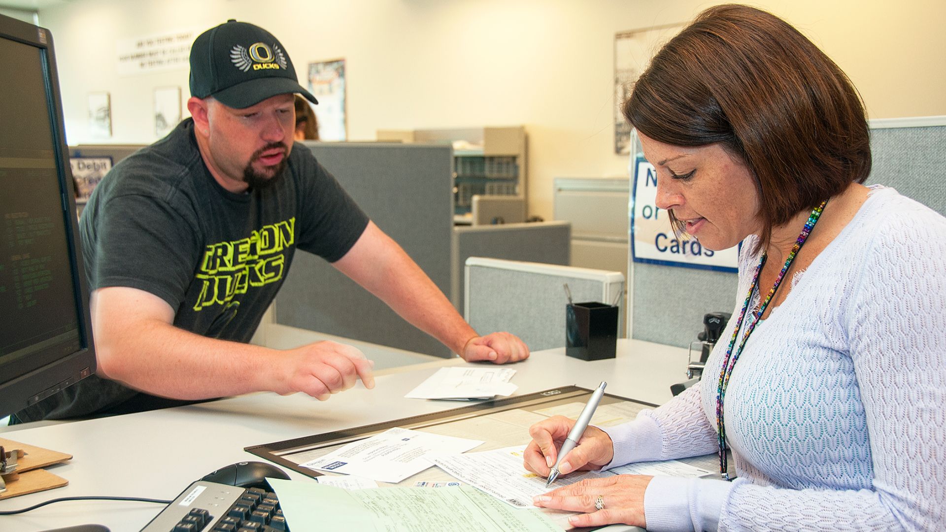 A clerk at DMV goes over a form with a customer.