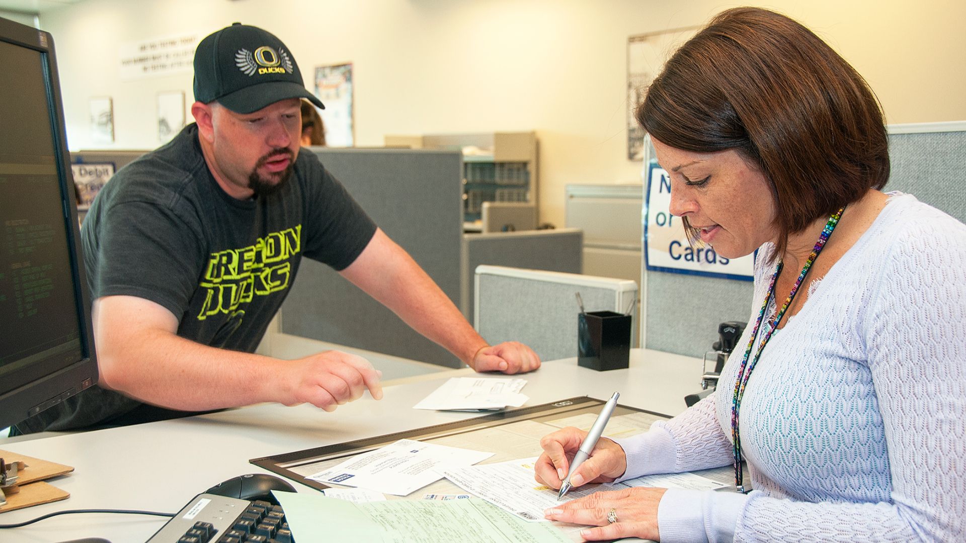 A clerk at DMV goes over a form with a customer.