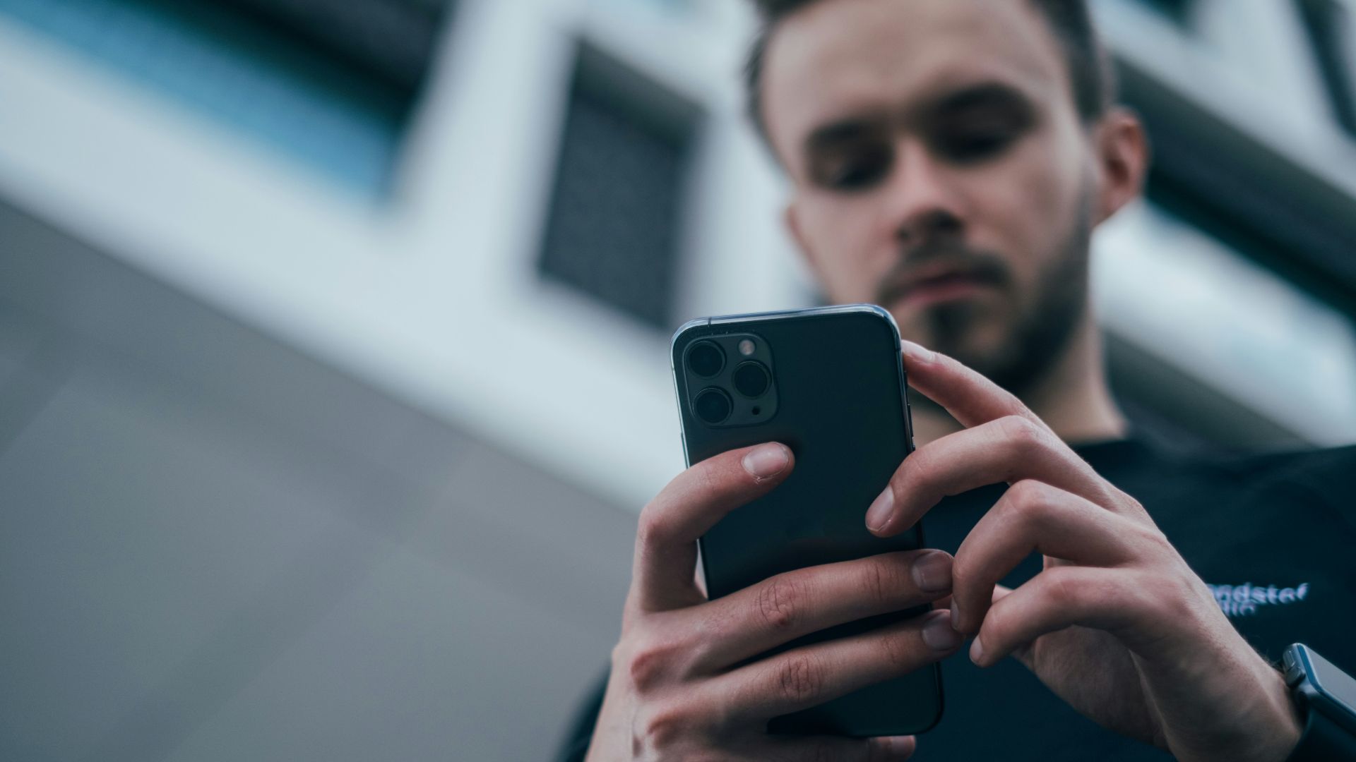 man wearing black sweater using smartphone
