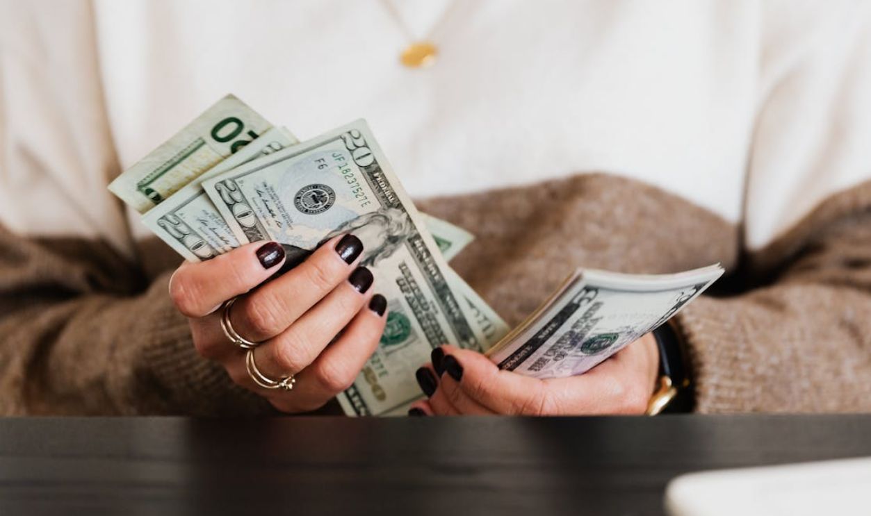 Close-up of hands counting US dollar bills, depicting finance and money handling